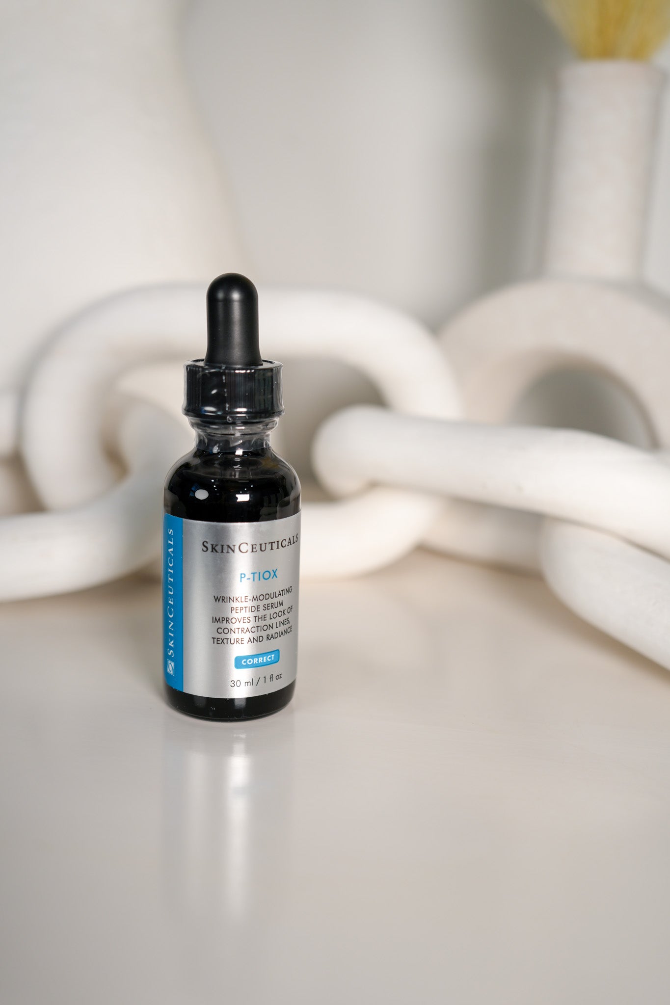 Skinceuticals serum bottle on a white surface with blurred background