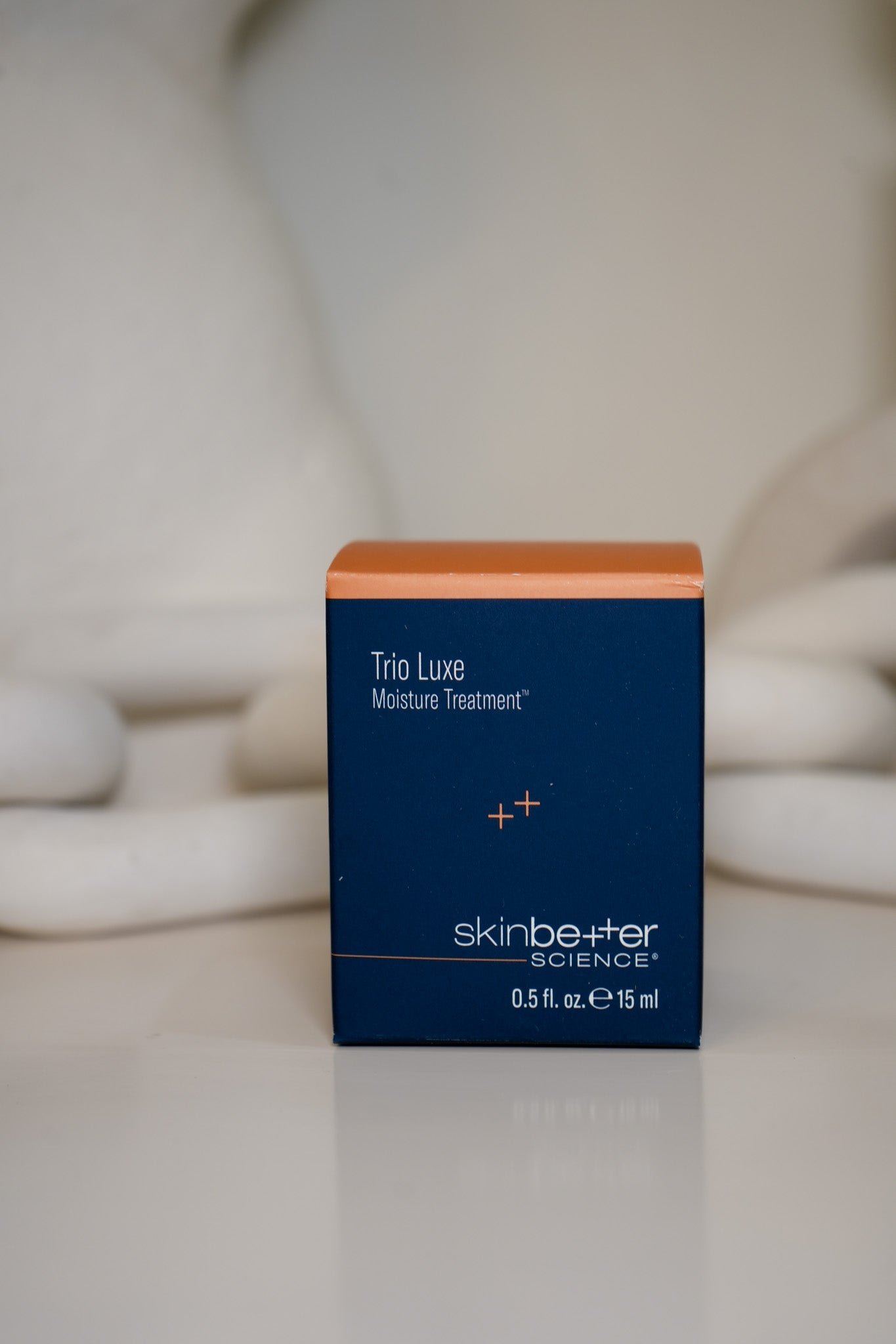 Blue skincare product box with orange top on a blurred background