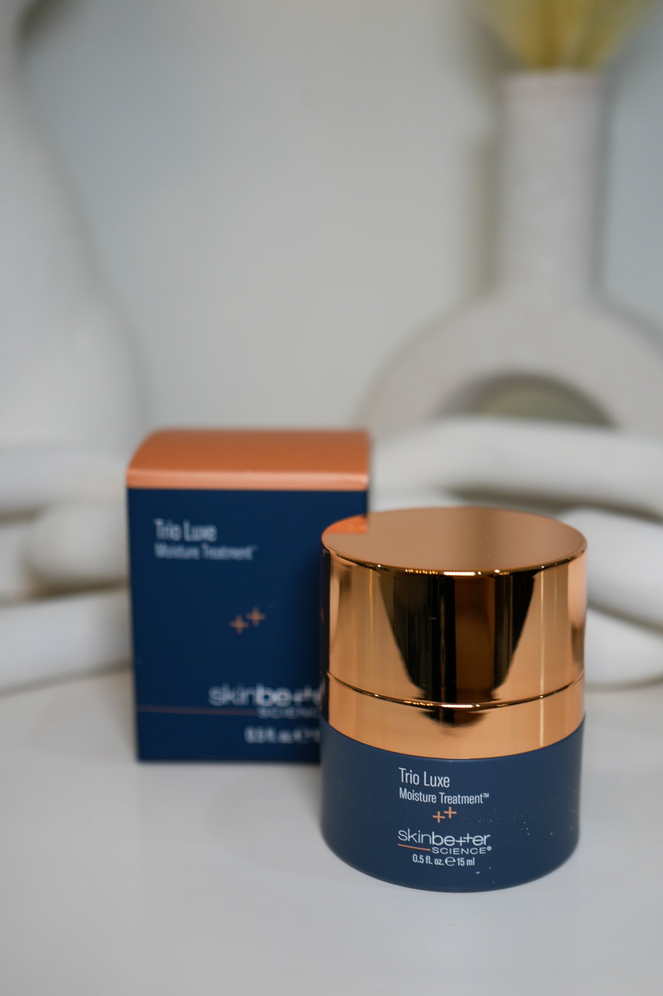 Skincare product with gold cap and blue container on a white surface