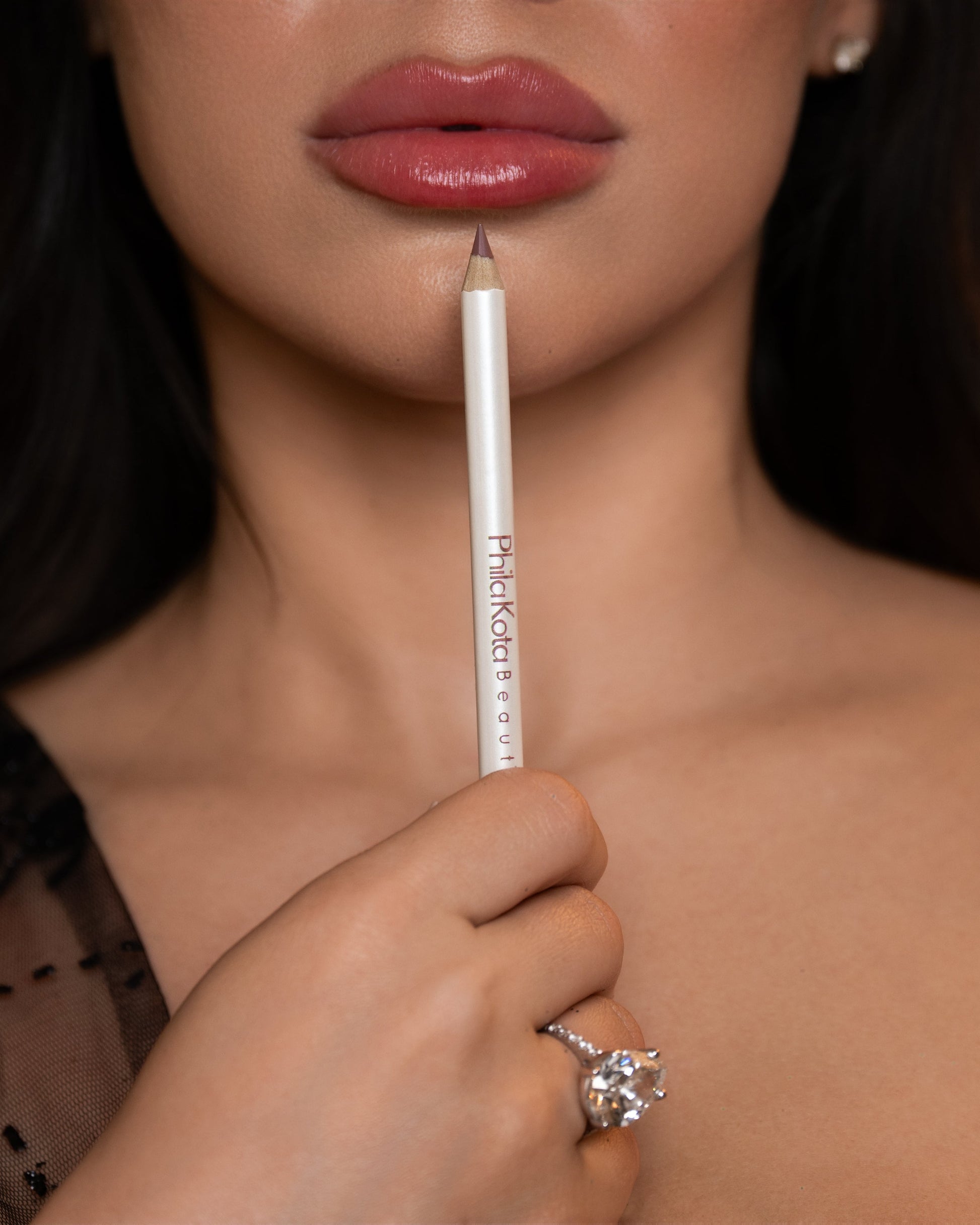 Woman holding a makeup pencil with a blurred background